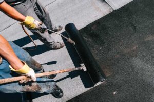 Roof workers inspect modern shingles, attic ventilation, solar roofing components, and moisture sensors on a residential roof.