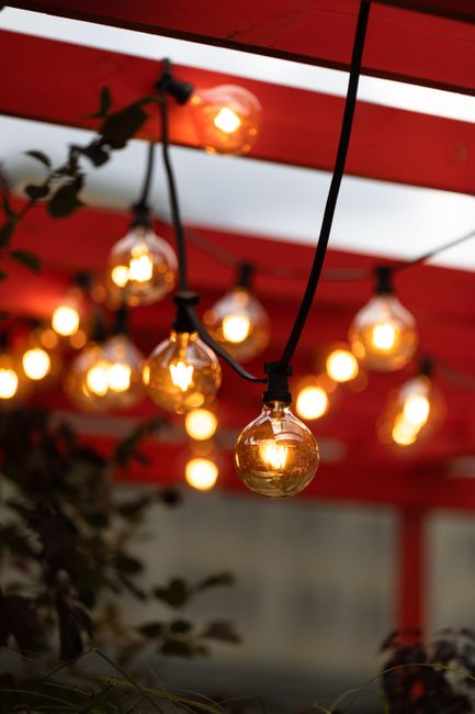 Person on a stable ladder attaching outdoor lights to house trim with plastic clips.